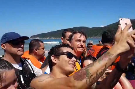 Bolsonaro passeia na praia e posa ao lado de apoiadores sem máscara